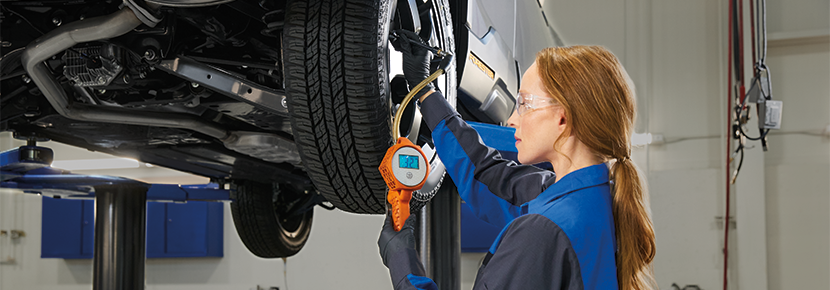 A Subaru technician checking tire pressure. | Competition Subaru of Smithtown in St James NY