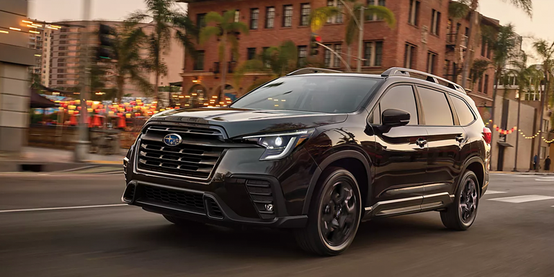 A dark-colored SUV is driving on a city street