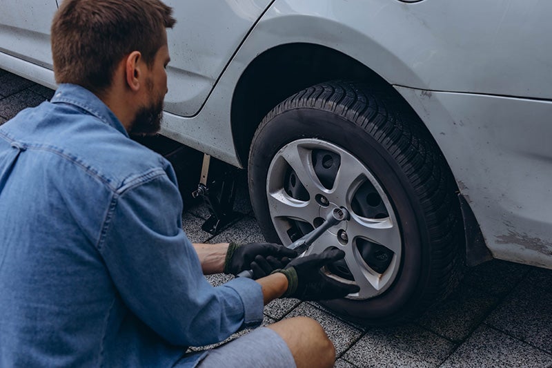Technician replacing or tightening lug nuts on a vehicle wheel during tire maintenance