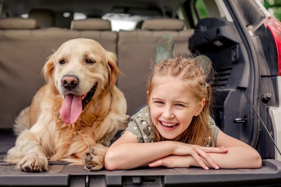Child and dog sitting in vehicle cargo area