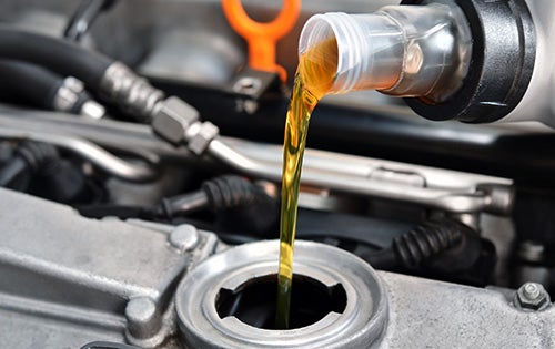 Engine oil being poured into a vehicle engine during routine oil change service and preventive maintenance