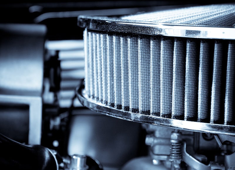 A close-up view of a cylindrical high-flow air filter mounted within an engine compartment