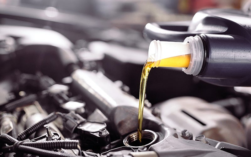 Engine oil being poured into a vehicle's engine through the oil fill port during a routine oil change service
