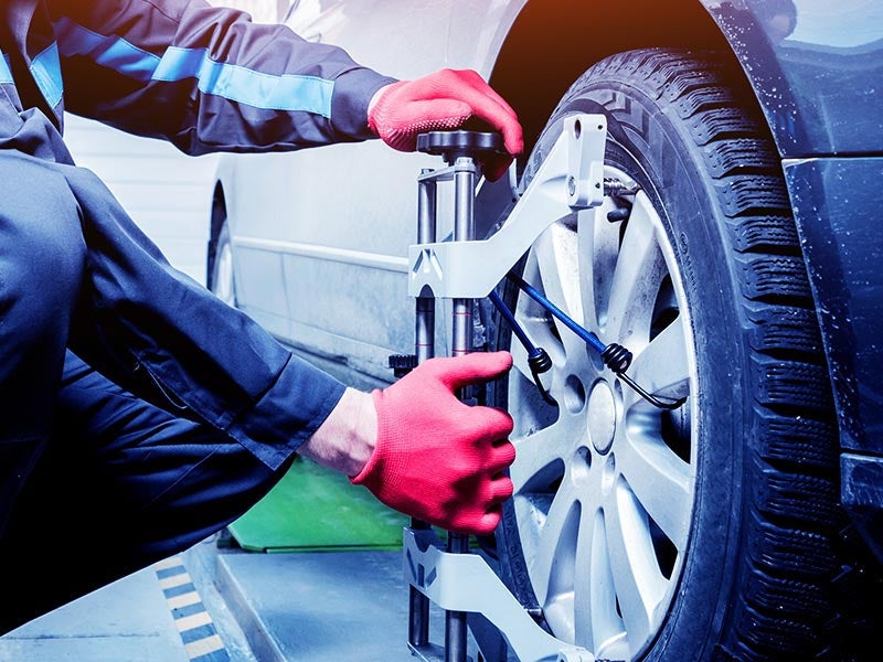 Vehicle wheel being adjusted with alignment equipment during a wheel alignment service.