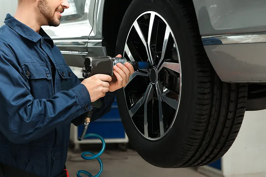Technician using a pneumatic impact wrench to install or tighten a vehicle wheel during tire service and maintenance