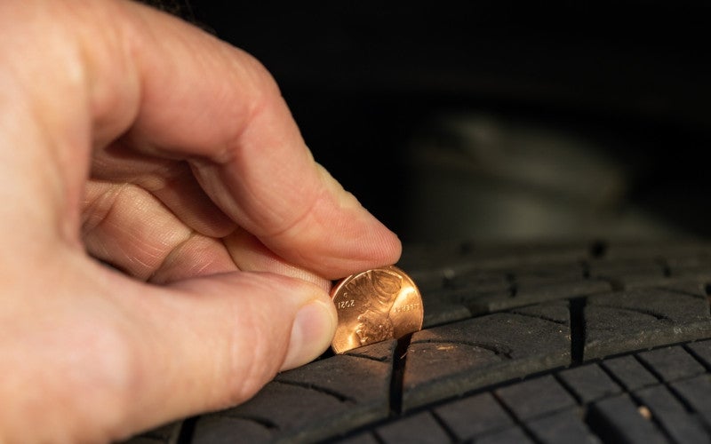 Close-up of a penny inserted into a tire tread to check tire tread depth and wear.