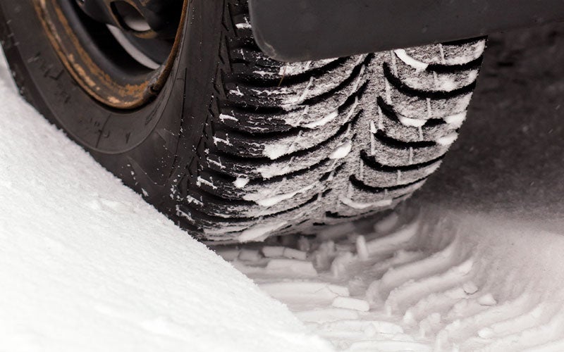 Tire tread gripping a snow-covered road, highlighting winter traction and cold-weather driving performance